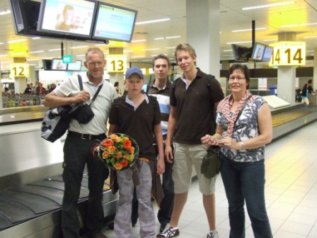 Terug op Schiphol, ontvangen door Bernadette, een vrijwilligster van Doe een wens met een bos bloemen